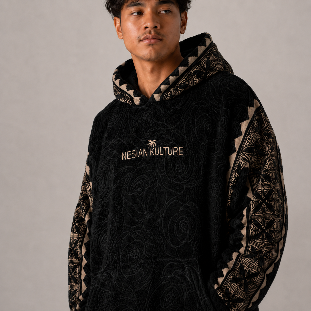 Nesian Kulture black and gold fleece snug hoodie close-up showing chest logo and textured fabric