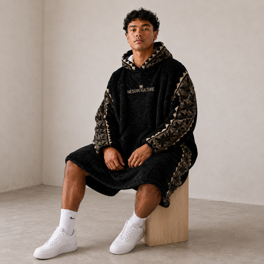 Nesian Kulture black and gold oversized snug hoodie, seated lifestyle view with patterned sleeves